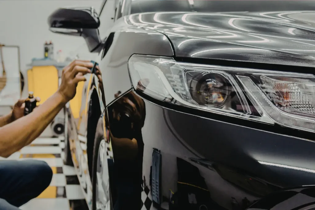 Technician performing wheel alignment service on gray sedan at auto repair shop in Orlando FL