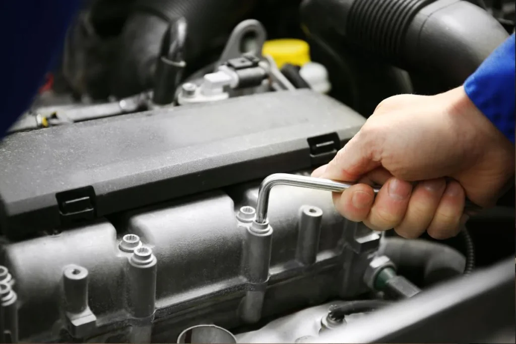 Close up of a mechanic using a wrench to tighten engine bolts during an exhaust flange repair kit installation