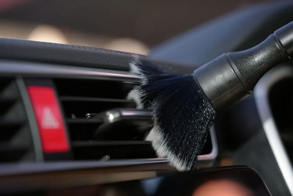 Cleaning car dashboard air vents to maintain proper airflow as part of routine car cooling system repair and maintenance