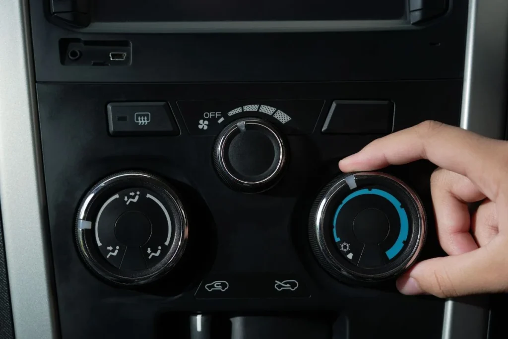 Automotive air conditioning repair: hand adjusting car AC controls